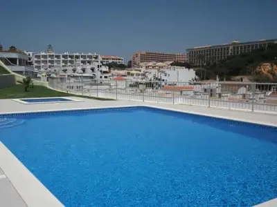 a large blue swimming pool with buildings in the background at Apartamento sobre a praia in Olhos de Água