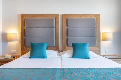 a bedroom with a large bed with blue pillows at 3HB Guarana - All Inclusive in Albufeira