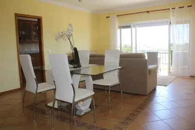 a living room with a glass table and white chairs at Vilamoura, Marina Sol T1 in Quarteira