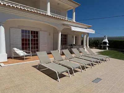 a row of lounge chairs sitting on a patio at Casa Alves - Villa with private heated swimming pool in Olhos de Água
