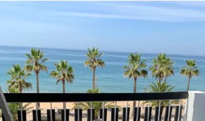 a balcony with a couch and chairs and the beach at Quarteira Beach Stunning Apartment in Quarteira
