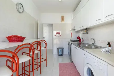 a kitchen with red chairs and a sink and a counter at Centralgarve - 1 Bedroom Apartment Near the Beach in Quarteira - Anglo Atlântico in Quarteira