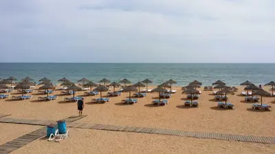 a bunch of chairs and umbrellas on a beach at Algarve Villa Albufeira Altos dos Caliços in Albufeira