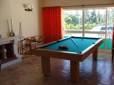 a pool table in a living room with a fireplace at Casa Coral in Albufeira