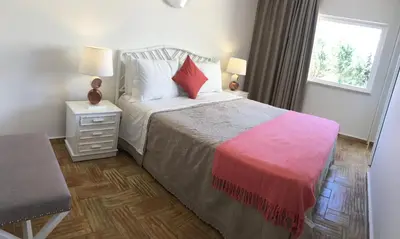a bedroom with a bed with a red blanket and a window at Casa Coral in Albufeira