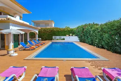 a swimming pool with chairs and a house at Villa White Sands - Private Oasis, Heated Pool, Beaches & Strip Nearby in Albufeira