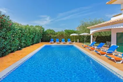a swimming pool with chairs and umbrellas at Villa White Sands - Private Oasis, Heated Pool, Beaches & Strip Nearby in Albufeira