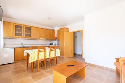 a kitchen with wooden cabinets and a table and chairs at Recanto da Galé by Umbral in Albufeira