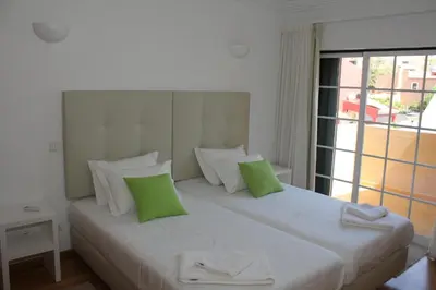 a bedroom with a large white bed with green pillows at Villa V2 Z in Olhos de Água