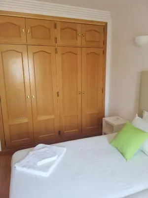 a bedroom with wooden cabinets and a white bed at Villa V2 Z in Olhos de Água