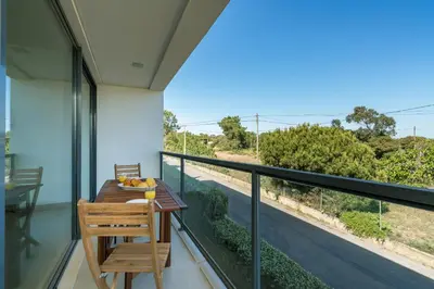a wooden table and chair on a balcony with a view at BmyGuest - Cavalo Preto Beach Apartment in Loulé