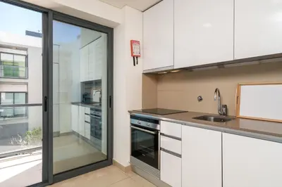 a kitchen with white cabinets and a sliding glass door at BmyGuest - Cavalo Preto Beach Apartment in Loulé