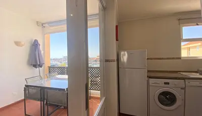a kitchen with a refrigerator and a table and a balcony at Penthouse Duplex Marina Plaza T1 HsR Marina Vilamoura in Vilamoura