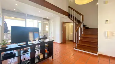 a living room with a television and a staircase at Penthouse Duplex Marina Plaza T1 HsR Marina Vilamoura in Vilamoura