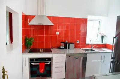 a red tiled kitchen with a stove and a sink at Casa aOrta in Faro