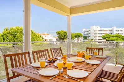 a wooden table with plates and glasses of orange juice at WHome | Vilamoura Family Apartment in Quarteira