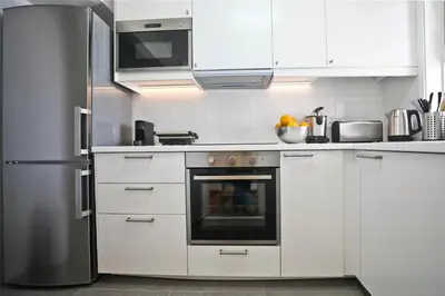 a kitchen with white cabinets and a stainless steel refrigerator at Albufeira Club 98 - O refúgio perfeito in Albufeira