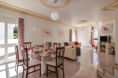 a dining room and living room with a table and chairs at Villa Santo Estevão in Olhos de Água