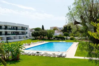 a large swimming pool with lounge chairs and a building at TAC - Vilamoura Center in Vilamoura