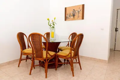 a dining room table with four chairs and a vase with flowers at TAC - Vilamoura Center in Vilamoura