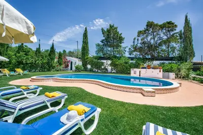 a swimming pool in a yard with lounge chairs and an umbrella at Villa Hideaway by Algarve Villa Holidays in Galé