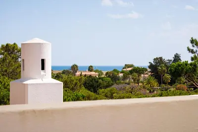 a patio with two chairs and an umbrella at Victory Village T1 & Rooftop terrace in Quinta do Lago