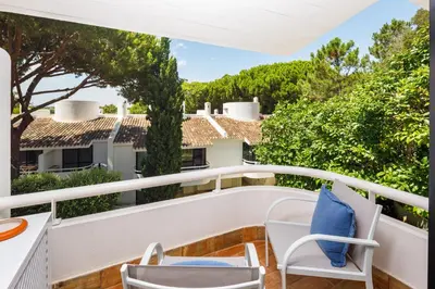 a balcony with a table and chairs and trees at Victory Village T1 & Rooftop terrace in Quinta do Lago