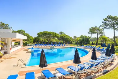 a swimming pool with chairs and umbrellas at Victory Village T1 & Rooftop terrace in Quinta do Lago