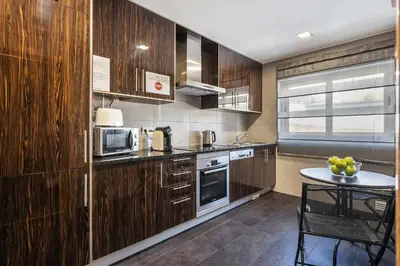 a kitchen with wooden cabinets and a table in it at Praia Mar by OCvillas in Albufeira