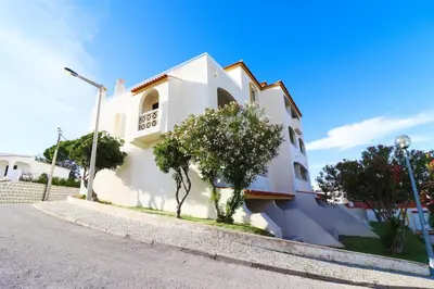 a white building with trees next to a street at Bellavista Jardim By BeGuest in Albufeira