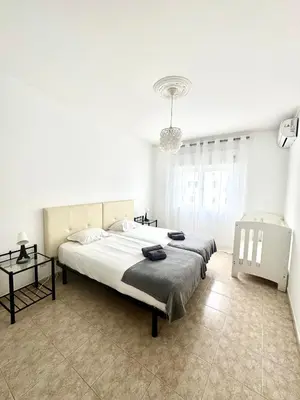a white bedroom with a large bed and a chandelier at Apartamento Millenium Vista Mar- 2 passos da Praia in Quarteira