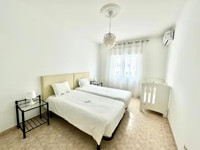 a white bedroom with a bed and a window at Apartamento Millenium Vista Mar- 2 passos da Praia in Quarteira