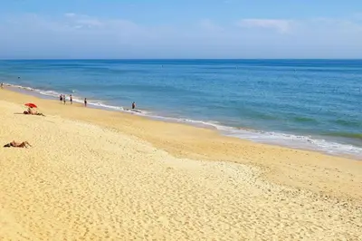 a group of people on a beach with the ocean at Apartamento Millenium Vista Mar- 2 passos da Praia in Quarteira
