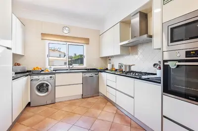 a kitchen with white cabinets and a washer and dryer at Villa Ericeira by OCvillas in Albufeira