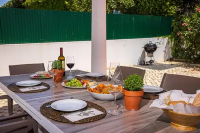 a table with plates of food and a bottle of wine at Villa Ericeira by OCvillas in Albufeira
