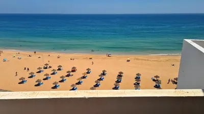 a beach with a bunch of chairs and umbrellas at Albufeira Beach Cliffs House in Albufeira