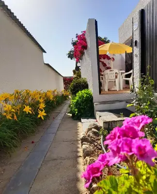 a garden with flowers and a table and an umbrella at Vila Planalto - Golfe - Entre o Golfe e o Mar in Vilamoura