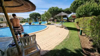 a man standing next to a swimming pool at Apartamentos Praia da Oura by Sunny Deluxe in Albufeira