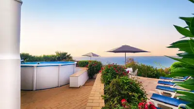a patio with a hot tub and chairs and an umbrella at Beira Mar by Check-in Portugal in Albufeira