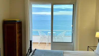 a bedroom with a door open to a balcony with chairs at Beira Mar by Check-in Portugal in Albufeira