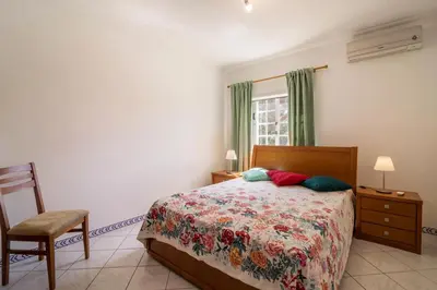 a bedroom with a bed and a chair and a window at Marjoh Al in Quarteira