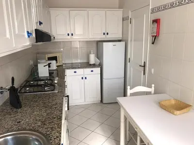 a kitchen with white cabinets and a white refrigerator at Marjoh Al in Quarteira