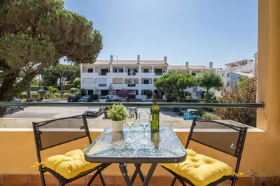 a table with two glasses and a bottle of wine on a balcony at Marjoh Al in Quarteira