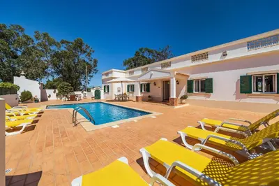 a villa with a swimming pool and yellow lounge chairs at Casa da Bia by OCvillas in Albufeira