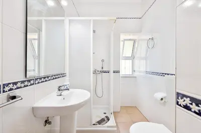 a white bathroom with a sink and a shower at Casa da Bia by OCvillas in Albufeira