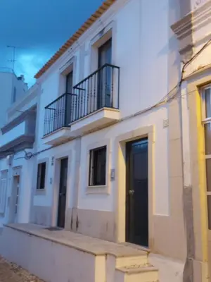 a white building with a black door and balcony at Casa Flor de Sal - moradia no Centro de Faro! in Faro
