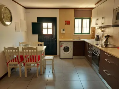 a kitchen with a table and chairs and a washing machine at Casa Flor de Sal - moradia no Centro de Faro! in Faro