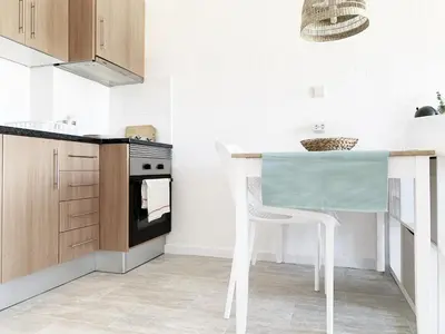 a kitchen with a white table and a white chair at Seaview Studio - 10 Min. Beach, Private Condo, Pool, Grill & Free Parking in Albufeira