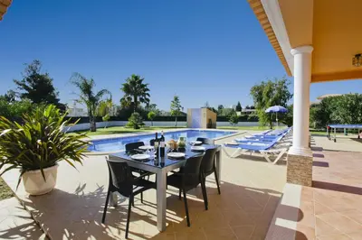 a patio with a table and chairs next to a pool at Villa João Paulo in Albufeira