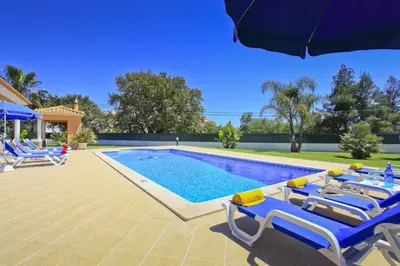 a swimming pool with lounge chairs and an umbrella at Villa João Paulo in Albufeira